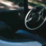 Car owner inspecting a sunlit sedan interior for the source of a bad smell