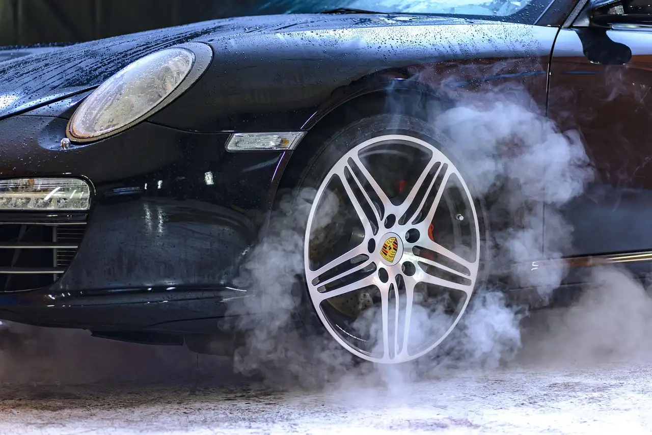 Person cleaning car wheels with spray and microfiber towels in a driveway