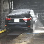 Foam cannon and foam gun beside a car wash setup in natural daylight