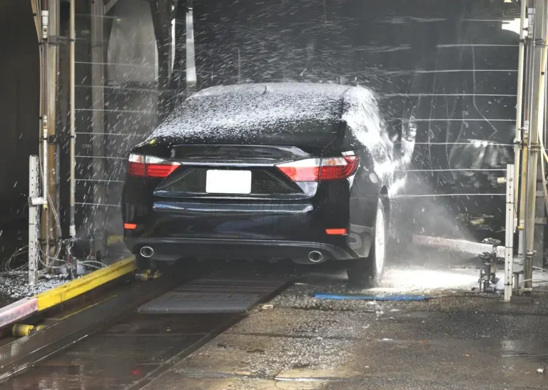 Foam cannon and foam gun beside a car wash setup in natural daylight