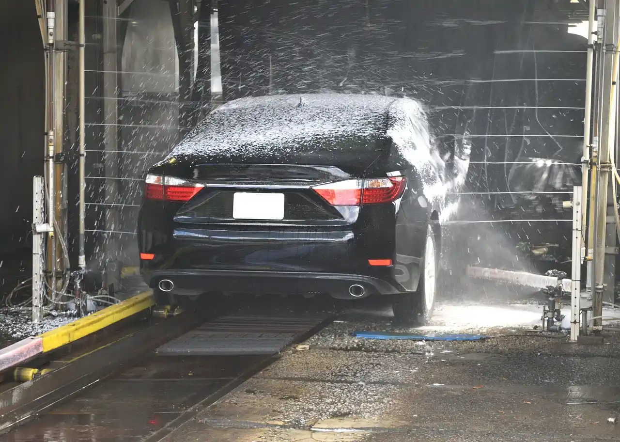 Foam cannon and foam gun beside a car wash setup in natural daylight