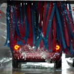Foam cannon coating a sedan with suds during a driveway car wash at home