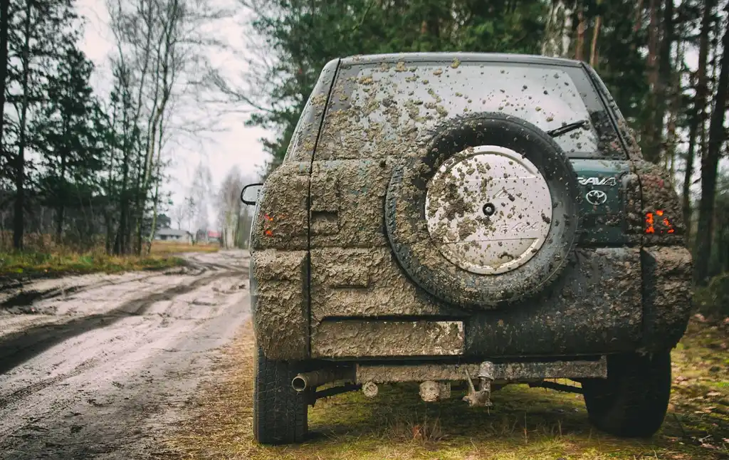 Front wheels of a sedan with heavier brake dust than the rear wheels in daylight