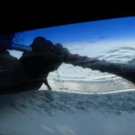 Person cleaning the interior windshield of a car with a microfiber towel in natural light