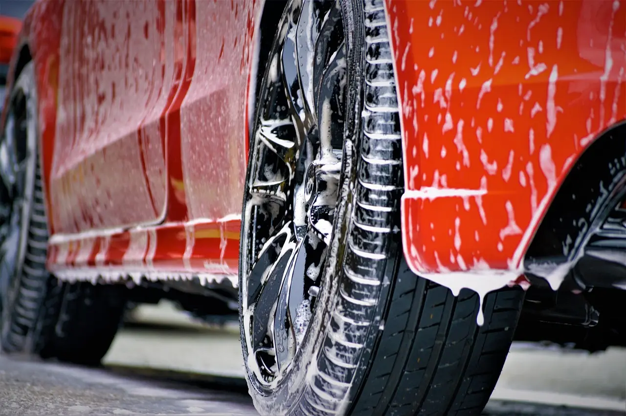 Microfiber towel and cotton towel held beside a dusty car hood in natural daylight
