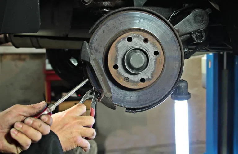 A car wheel with light gray brake dust on the rim and visible brake rotor in daylight