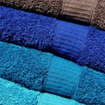 Microfiber towel being used on a car hood with clear coat reflections in natural light