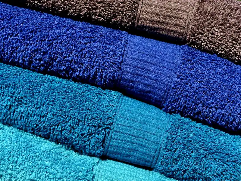 Microfiber towel being used on a car hood with clear coat reflections in natural light